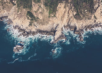 Aerial view of rugged coastline with crashing ocean waves
