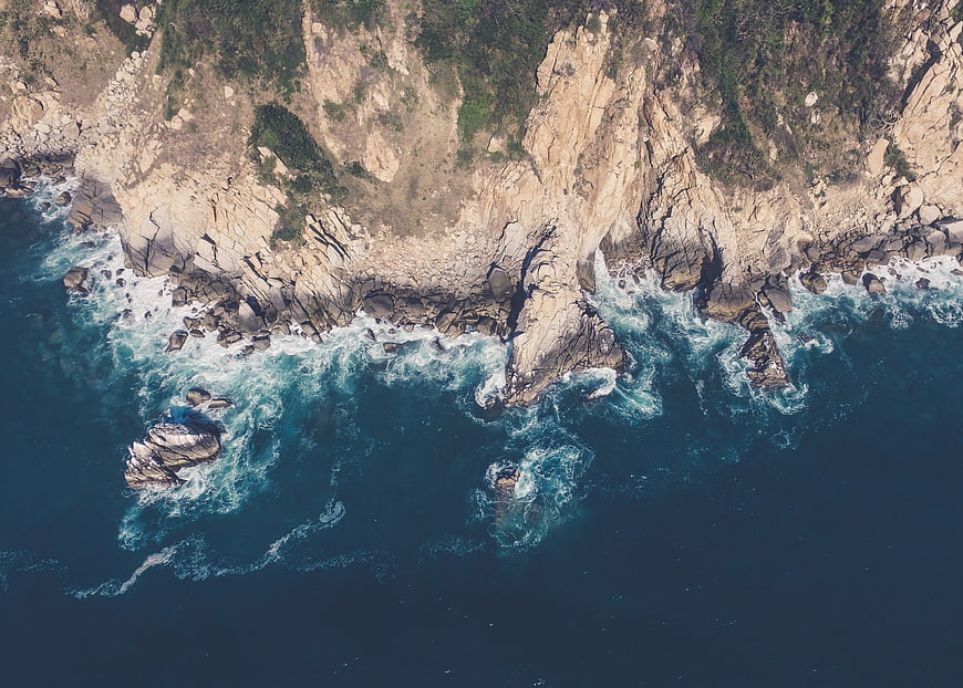 Aerial view of rugged coastline with crashing ocean waves