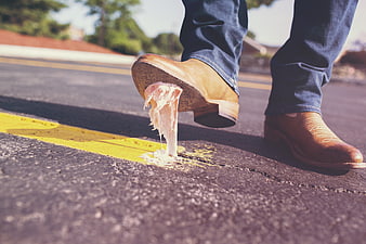 Man stepping on chewing gum on asphalt street