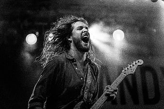 Passionate male guitarist singing on stage in black and white