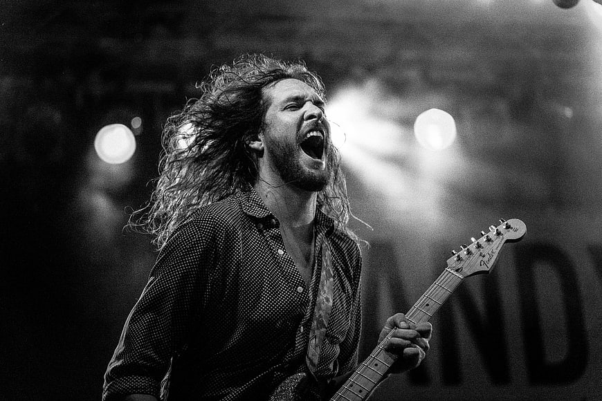 Passionate male guitarist singing on stage in black and white