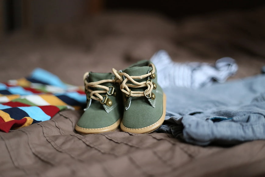 Baby Green Sneakers with Clothes on Bed