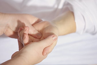 Close-up of Adult Holding Baby's Hand on White Bed