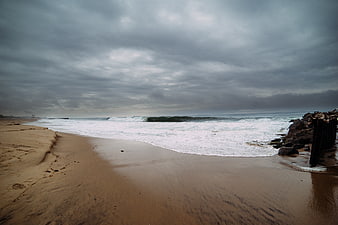 Dramatic Stormy Beach with Crashing Waves and Rocky Jetty
