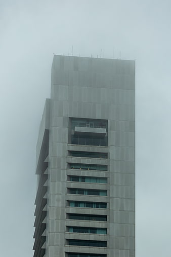 Tall modern skyscraper disappearing into thick fog