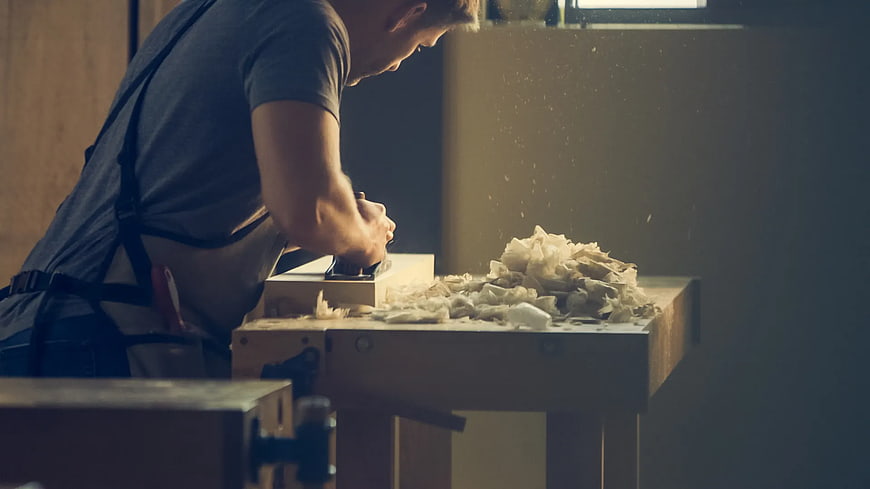 Carpenter Planing Wood in Workshop