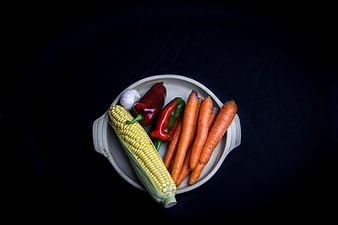 Fresh vegetables in ceramic bowl on black background