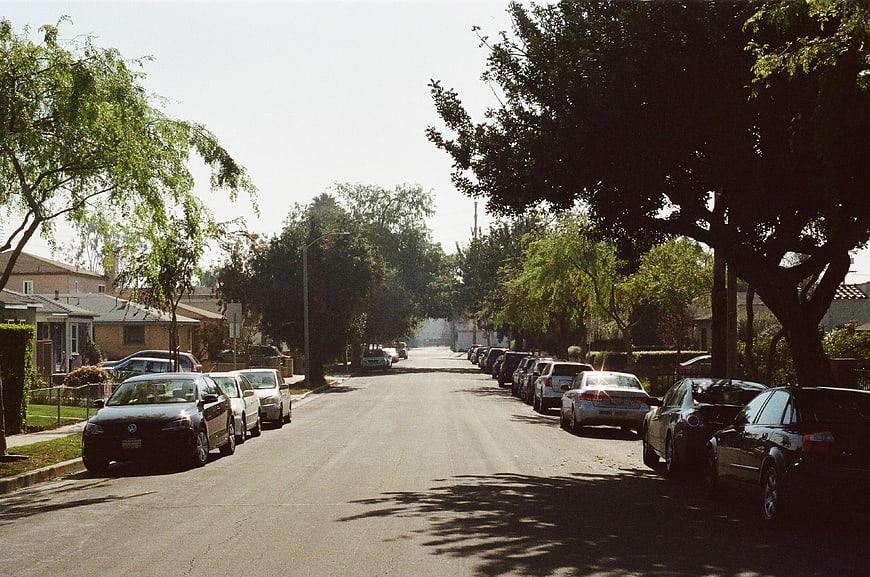 Sunny Residential Street with Parked Cars and Trees