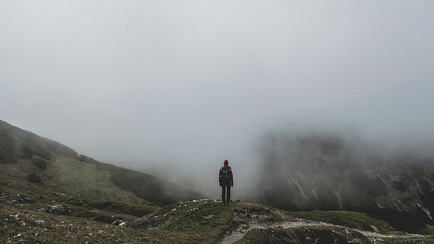 Lone Hiker Standing on Misty Mountain Ridge