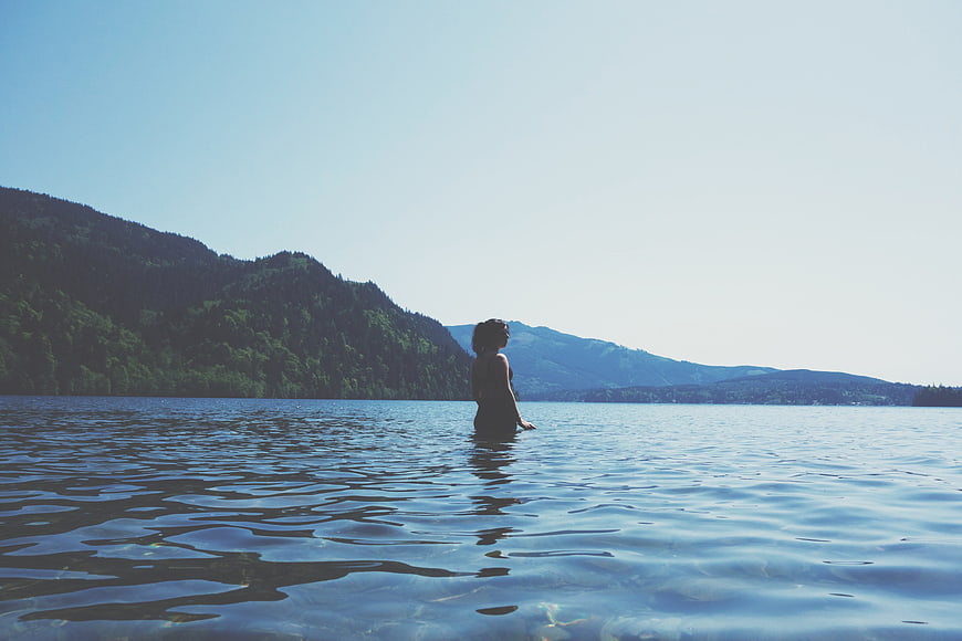 Woman Standing in Lake Water with Mountain Background