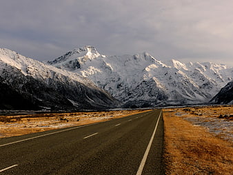 Snowy mountain highway landscape with golden grass