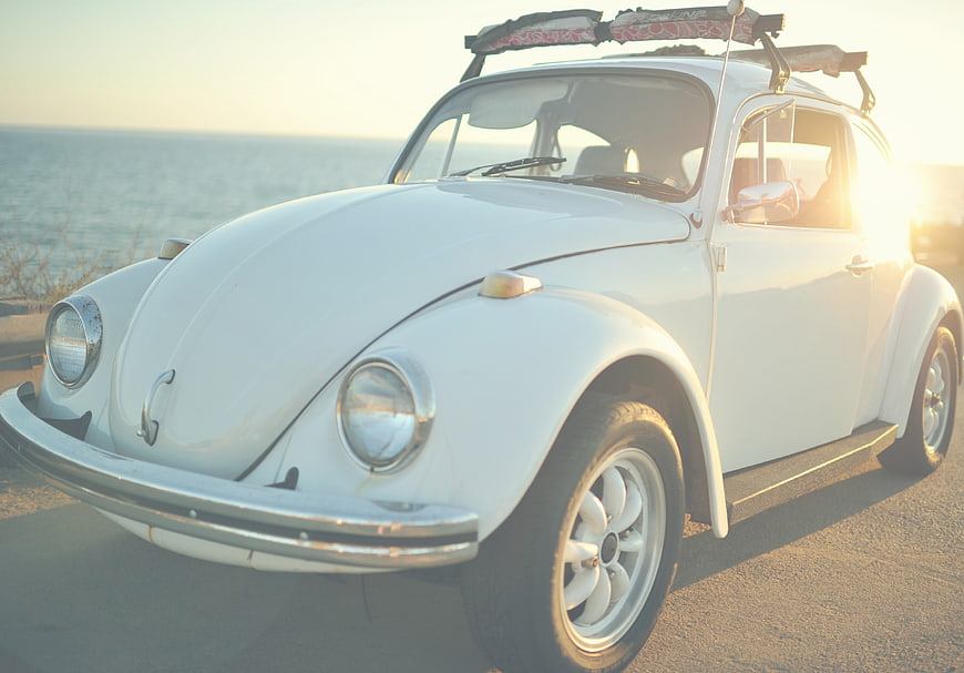 Vintage White Volkswagen Beetle at Sunset by the Ocean