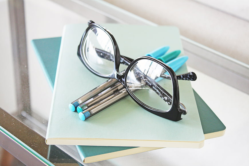 Black Glasses and Pens on Mint Notebooks