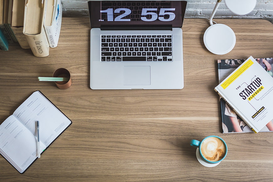 Flat lay workspace with laptop, coffee, and startup book