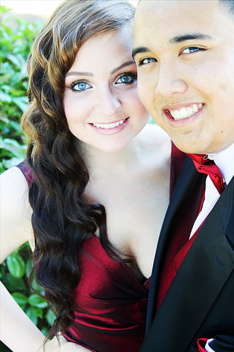 Smiling young couple in formal red and black attire outdoors