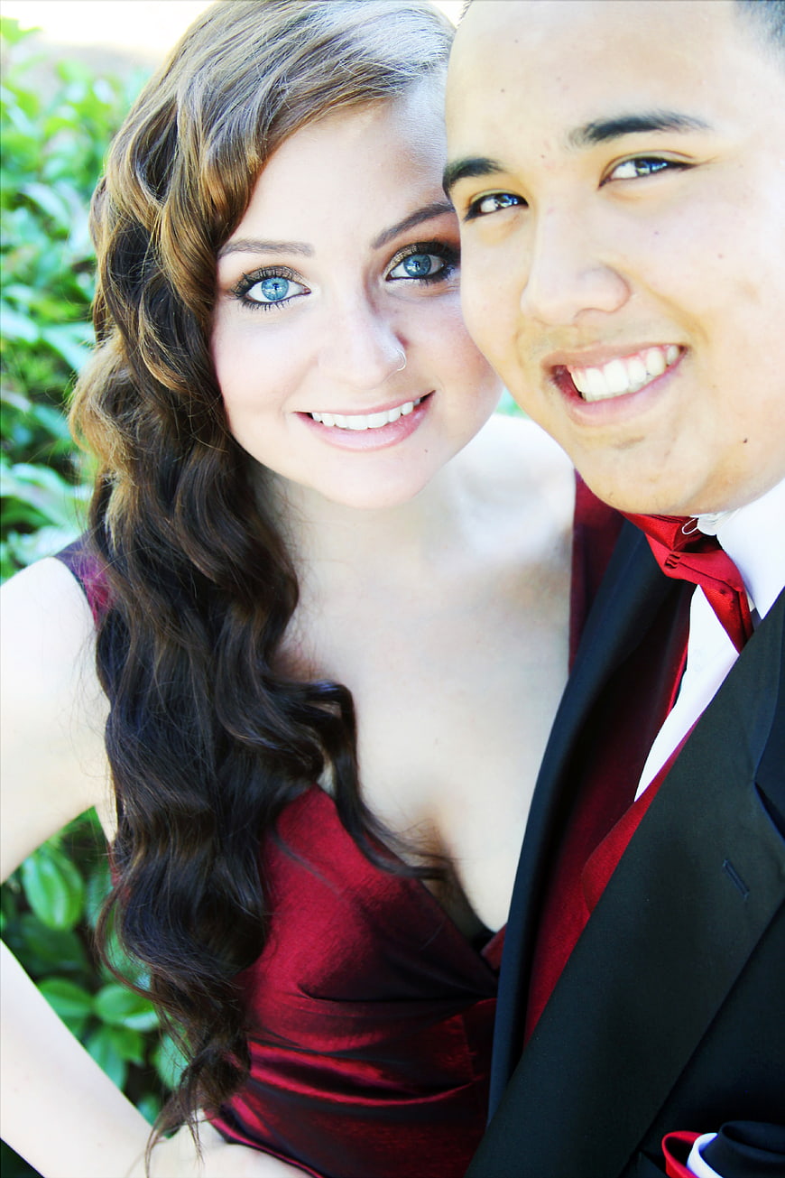 Smiling young couple in formal red and black attire outdoors