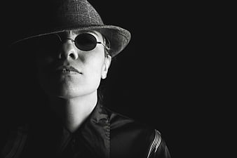 Mysterious woman in fedora and sunglasses black and white portrait