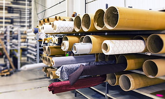 Large rolls of fabric and paper stored on industrial warehouse shelves
