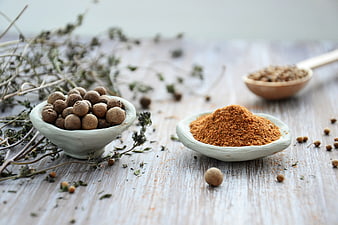 Dried spices and herbs in ceramic bowls on rustic wood