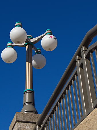 White Globe Street Lamp with Love Text Against Blue Sky
