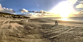Father and son walking on sandy beach at sunset