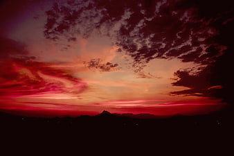 Dramatic red sunset sky over dark mountain silhouette