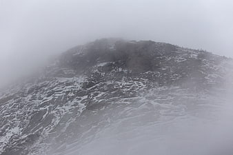 Snowy mountain peak shrouded in thick fog and mist