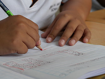 Child Writing Numbers in Graph Paper Notebook