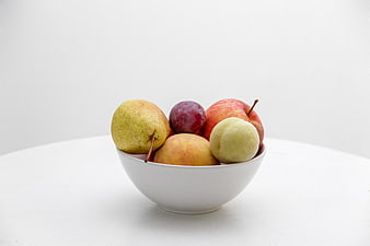 White bowl of fresh fruit on white background