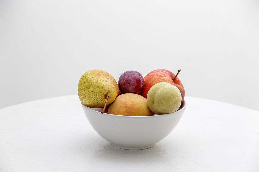 White bowl of fresh fruit on white background