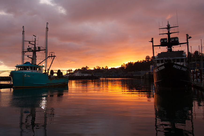 Fishing boats docked in harbor at sunset with colorful sky