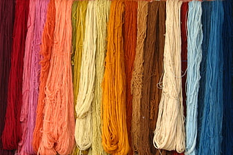 Colorful skeins of yarn hanging in a rainbow pattern