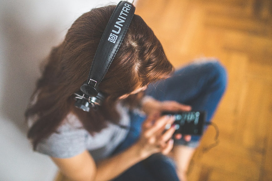 Woman with headphones listening to music on smartphone