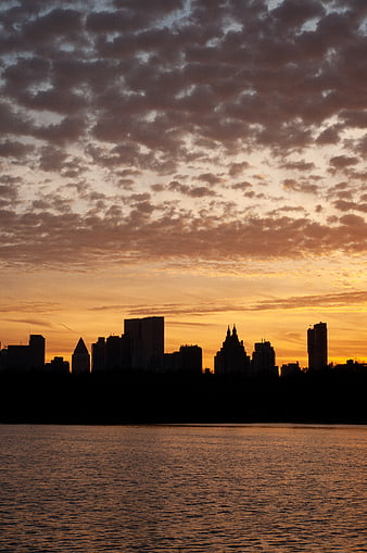Dramatic City Skyline Silhouette at Sunset Over Water