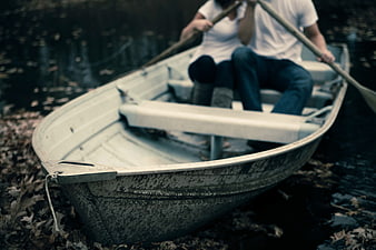 Couple rowing a vintage boat in autumn leaves