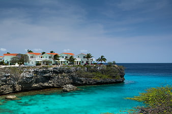 White resort houses on a rocky cliff overlooking turquoise ocean