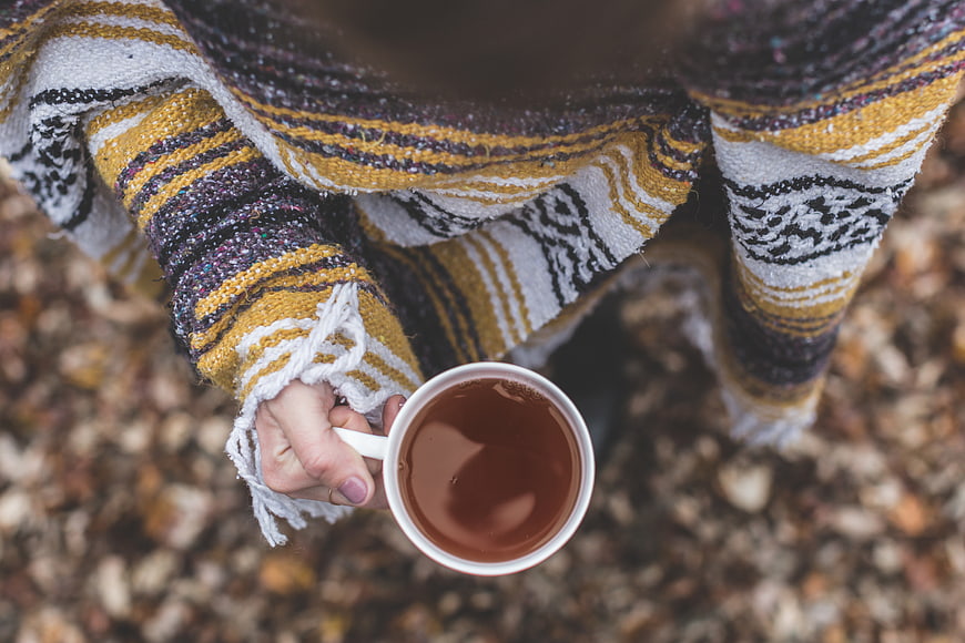 Woman holding cup of tea in cozy knit sweater