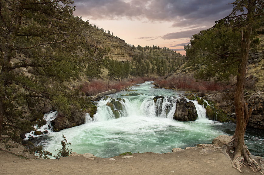 Scenic waterfall in a forested canyon at dusk
