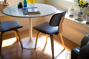 Modern white round table with wooden chairs in sunlit room