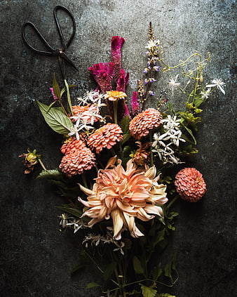 Flat lay of colorful summer flowers and vintage scissors on dark background