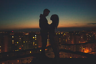 Silhouette of couple embracing on rooftop at dusk