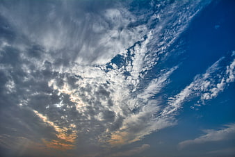 Dramatic blue sky with textured white clouds and sunlight