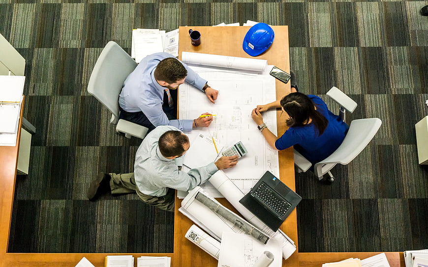 Overhead view of architects collaborating on blueprints