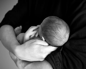 Black and White Photo of Sleeping Newborn in Arms