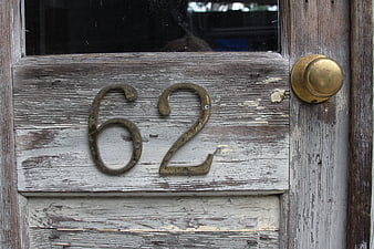 Weathered wooden door with brass number 62 and knob