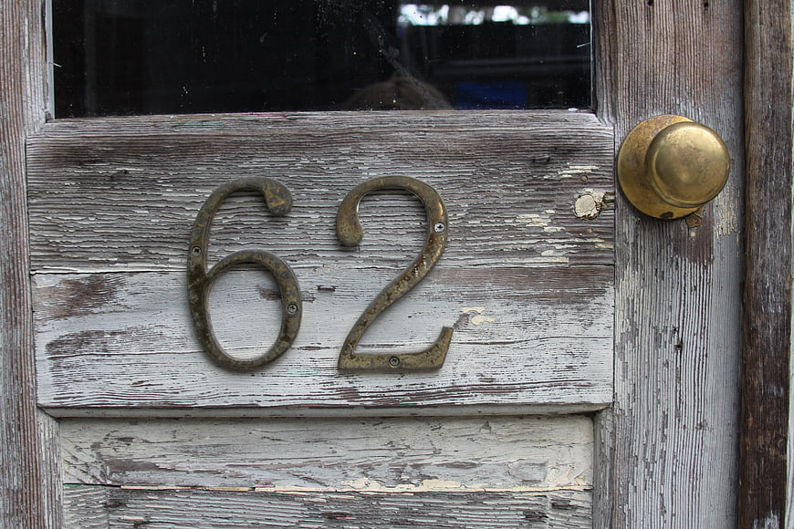 Weathered wooden door with brass number 62 and knob