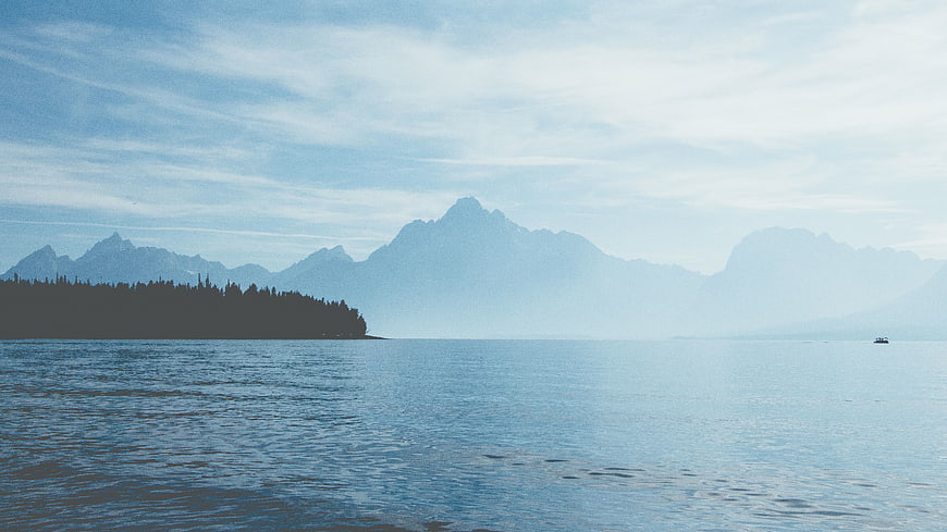Serene Lake Landscape with Distant Mountains and Forested Shore