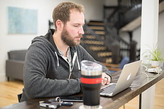 Bearded man working on laptop at home office desk