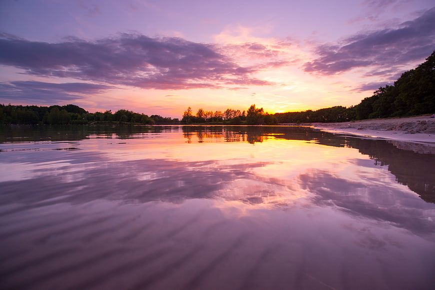 Vibrant Sunset Reflection on Calm Lake Water