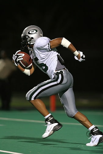 Football Player Running with Ball at Night